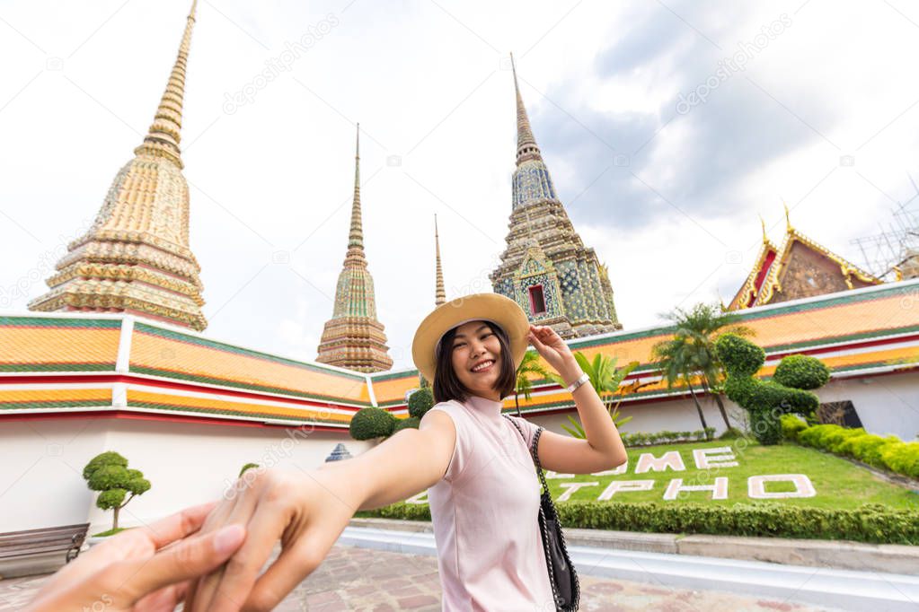 Tourist women with hat leading man to travel in Wat Pho temple with pagoda