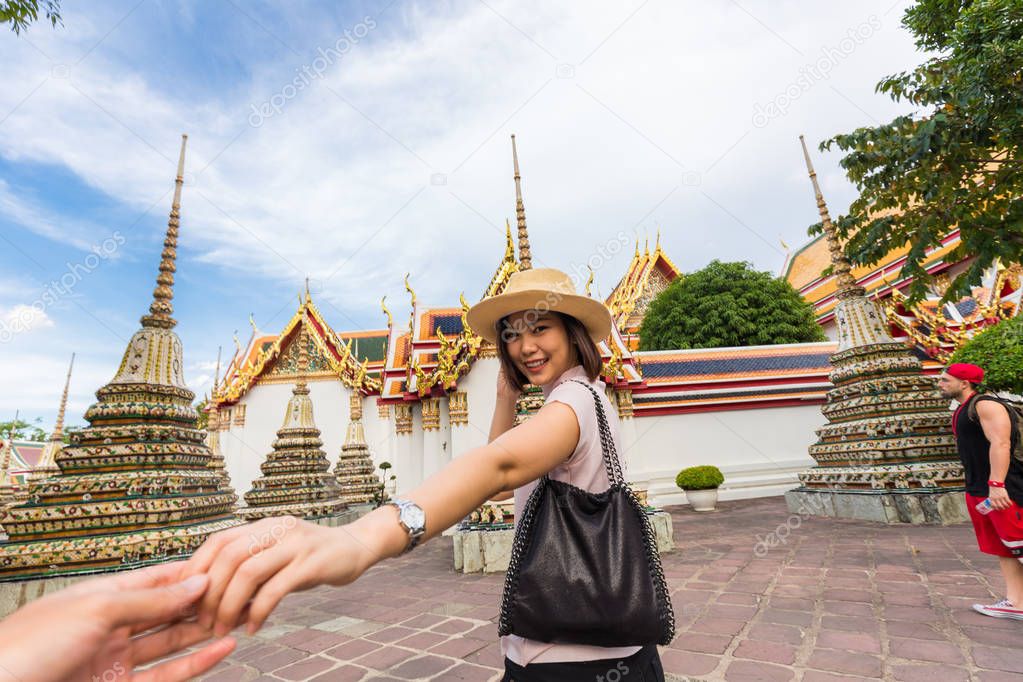 Tourist women with hat leading man to travel in Wat Pho temple with pagoda