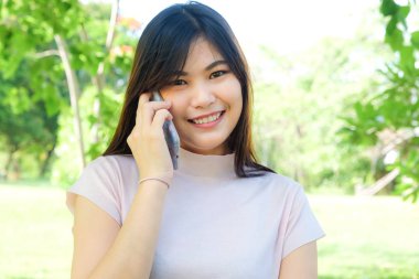 Güzel genç Asyalı kadınlar sosyal medya ve internet bankta oturan için cep telefonu kullanmak