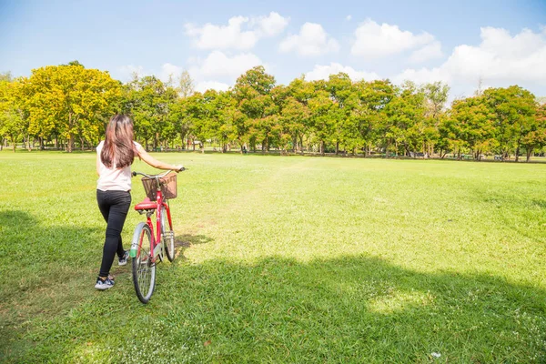 绿色草甸公共公园的年轻亚洲妇女与自行车 — 图库照片