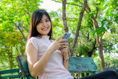 Kullanım cep telefonu genel parkta bankta siting rahatlatıcı gülümseyen kadın