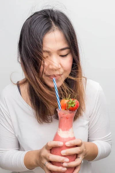 Funny asian women drinking strawberry smoothie homemade on white background