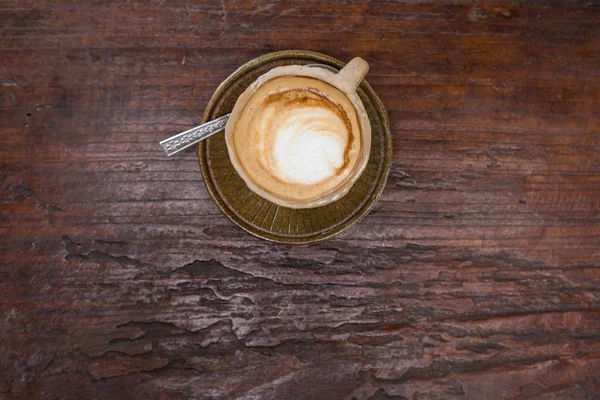 Latte art café chaud dans la tasse en pierre sur table en bois — Photo