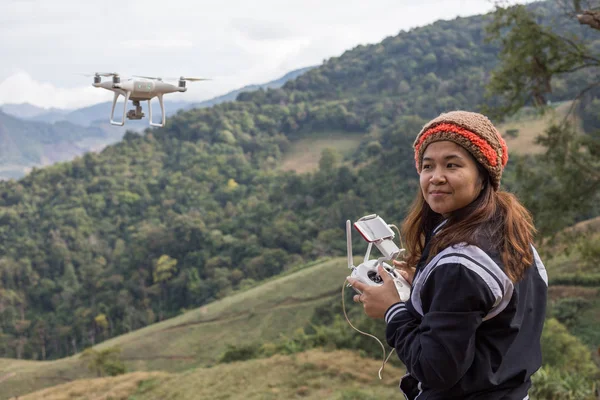 Women drive a drone quadcoppter via remote controller on the mountain field and take picture