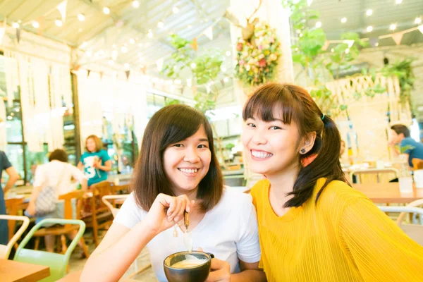 Beber con la amiga de dos mujeres sonrientes riendo mientras chismorrean —  Fotos de Stock