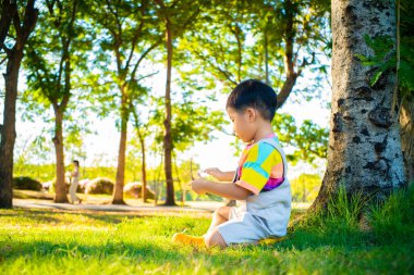 Mutlu çocuk parkta yürüyor yaz günbatımında çimenlerde oynuyor.