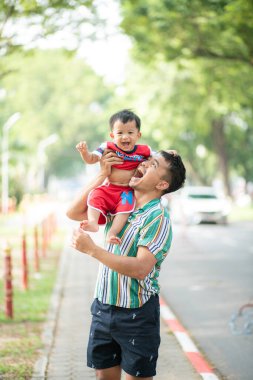 Bebeğim yeşil halk parkında babasıyla oynuyor. Komik çocuk mutlu.