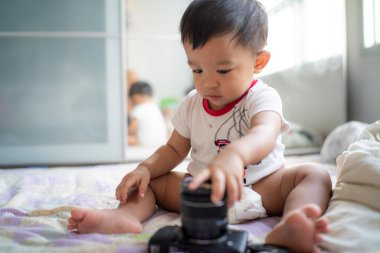 Sevimli erkek bebek rahat bir odada kamerayla oynuyor.