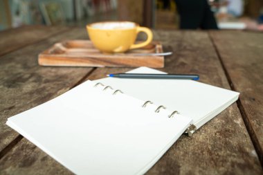 Tahta sehpanın üzerinde boş defterli sıcak kahve fincanı. Yazar konsepti.