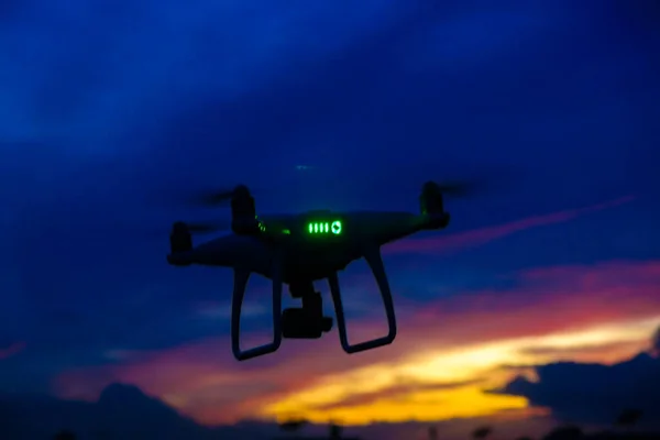 Quadcopter drone flying over city building sunset sky with cloud modern transport