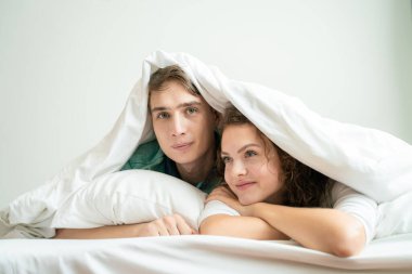 Sabahları beyaz battaniye yatak odasında yatan komik, sevgi dolu bir çift.