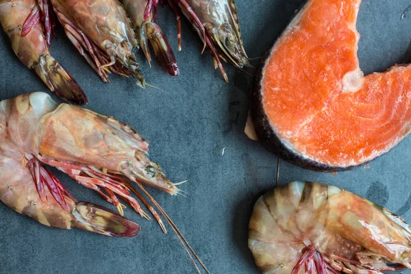 Fresh salmon fish with sea prawn shrimp on black plate, Seafood