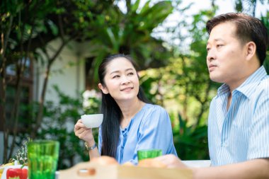 Yaşlı emekli çift kahve içiyor ve parkta konuşuyor, Asyalı çift.