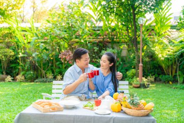 Yaşlı emekli çift kahve içiyor ve parkta konuşuyor, Asyalı çift.