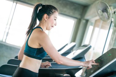 Modern spor salonunda koşu bandında koşan zeki Asyalı kadınlar