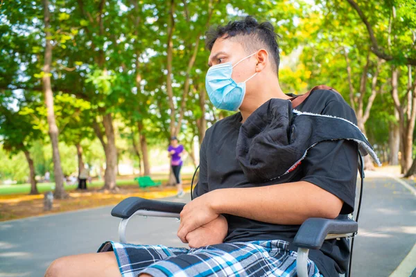 マスクで市内の緑の公園に車椅子に座っている人を無効にするCoid19健康的なコンセプト — ストック写真
