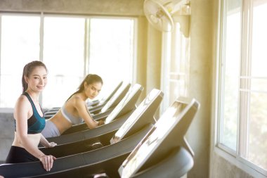 Spor salonunda koşu bandında çalışan bir grup kadın kardiyo tartısı kaybı konsepti yapıyor.