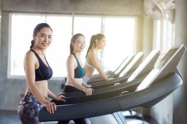 Spor salonunda koşu bandında çalışan bir grup kadın kardiyo tartısı kaybı konsepti yapıyor.