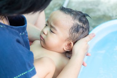Yeni yürümeye başlayan erkek bebek, ailesiyle birlikte havuzda kürek çekiyor.