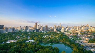 Bangkok şehir merkezindeki modern ofis binaları ve apartmanların çevresindeki Lumpini parkı manzarası. Tayland, Bangkok 'ta günbatımı gökyüzü bulutları var..