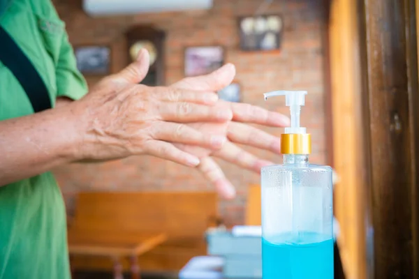 Coronavirus old women hand sanitizer sanitiser gel for clean hands hygiene corona virus spread prevention. Woman using alcohol to washing hands.