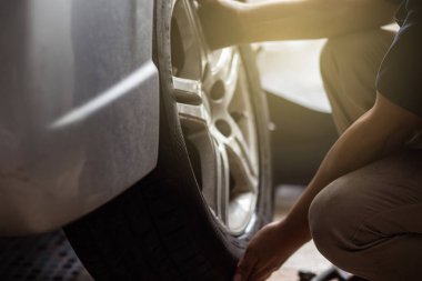 Mekanik araba garajı değişiyor ve arabanın lastiğini mekanik stabil motorla değiştiriyor.