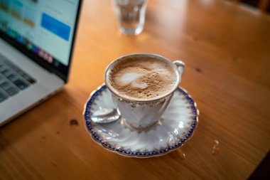 Sıcak aroma cappuccino kahve fincanı ev yapımı ev yapımı WFH konseptiyle evden ahşap masa işi yapıyor.