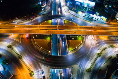 Gece kavşak şehir yolu kavşağında araç ışığı hava görüntüsü var.