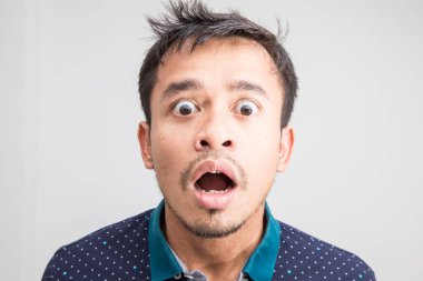 Genç Asyalı adamın portresi beyaz arka planda şok edici yüz ifadesi