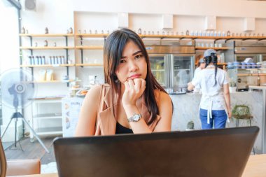 Modern kahve dükkanında oturan iş kadınları bir fincan kahveyle dizüstü bilgisayar kullanıyorlar.