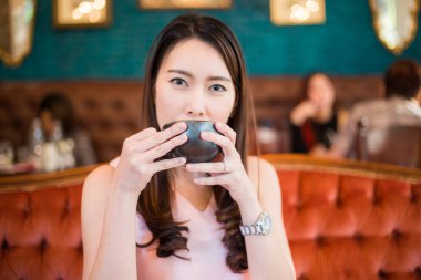 Lüks kanepede oturmuş, kaliteli kafede sıcak kahve içen hoş kadınlar.