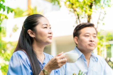 Yaşlı emekli çift kahve içiyor ve parkta konuşuyor, Asyalı çift.