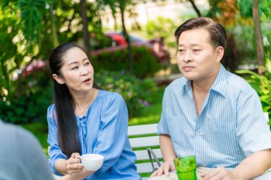 Yaşlı emekli çift kahve içiyor ve parkta konuşuyor, Asyalı çift.