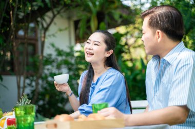 Yaşlı emekli çift kahve içiyor ve parkta konuşuyor, Asyalı çift.