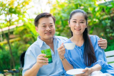 Yaşlı emekli çift kahve içiyor ve parkta konuşuyor, Asyalı çift.