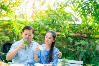 Yaşlı emekli çift kahve içiyor ve parkta konuşuyor, Asyalı çift.