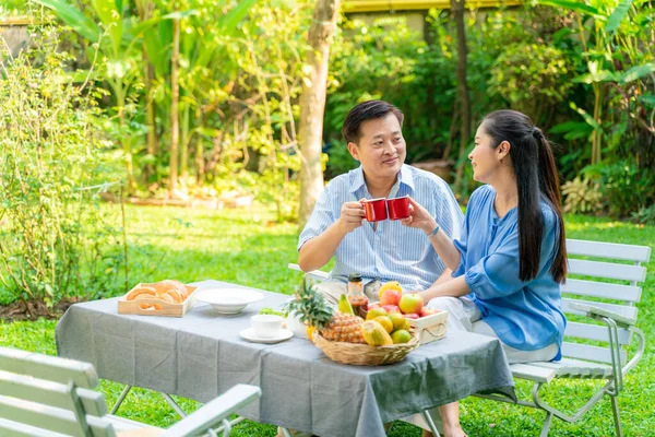 elderly couple drinking coffe and talking in park, Asian couple