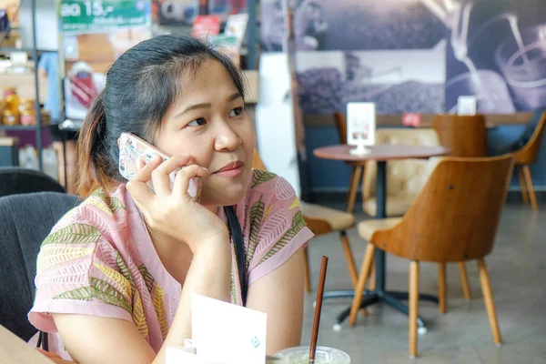 妇女坐在超市咖啡店的咖啡店里 一边用手机交谈 — 图库照片