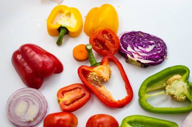 Beyaz arka planda dilimlenmiş renkli sebze seti, sağlıklı besin düzlüğü