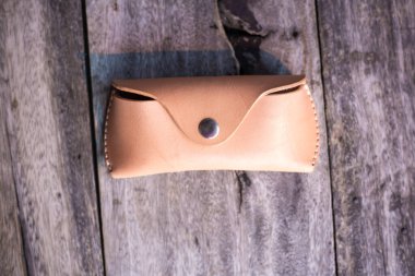 Hakiki deri gözlük çantası ahşap arka planda el yapımı, el işi.