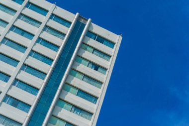 Yüksek gökdelen modern bina mavi gökyüzü arkaplanına karşı aşağıdan bakıyor