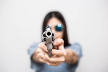 Akıllı güzel kadınlar beyaz arka planda tabancayı kameraya doğrultuyor.