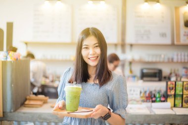 Mutlu gülümseyen Asyalı kadınlar buz eşliğinde yeşil çay içerler.