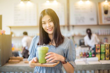 Mutlu gülümseyen Asyalı kadınlar buz eşliğinde yeşil çay içerler.