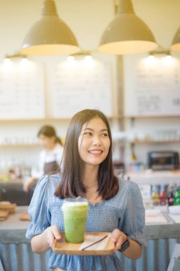 Mutlu gülümseyen Asyalı kadınlar buz eşliğinde yeşil çay içerler.