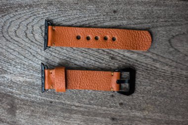 El yapımı kahverengi deri saat ahşap arka planda el işi.