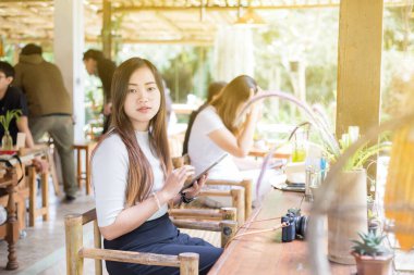Yerel kahve dükkanında oturan Asyalı iş kadınları tablet bilgisayarda çalışıyorlar.