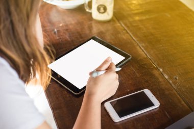 Yerel kahve dükkanında oturan Asyalı iş kadınları tablet bilgisayarda çalışıyorlar.