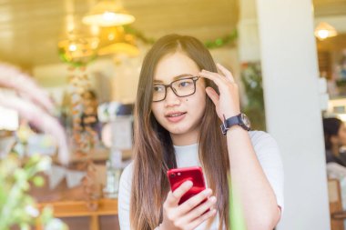 Çekici Asyalı kadınlar kafede otururken akıllı telefon iletişim kavramını kullanırlar