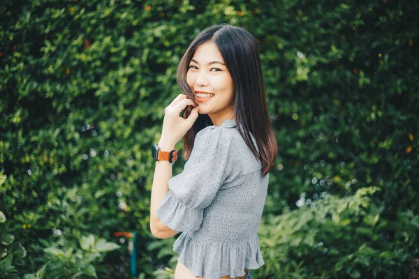 ファッションアジアの美しい女性フリック黒髪で緑の葉の背景 — ストック写真